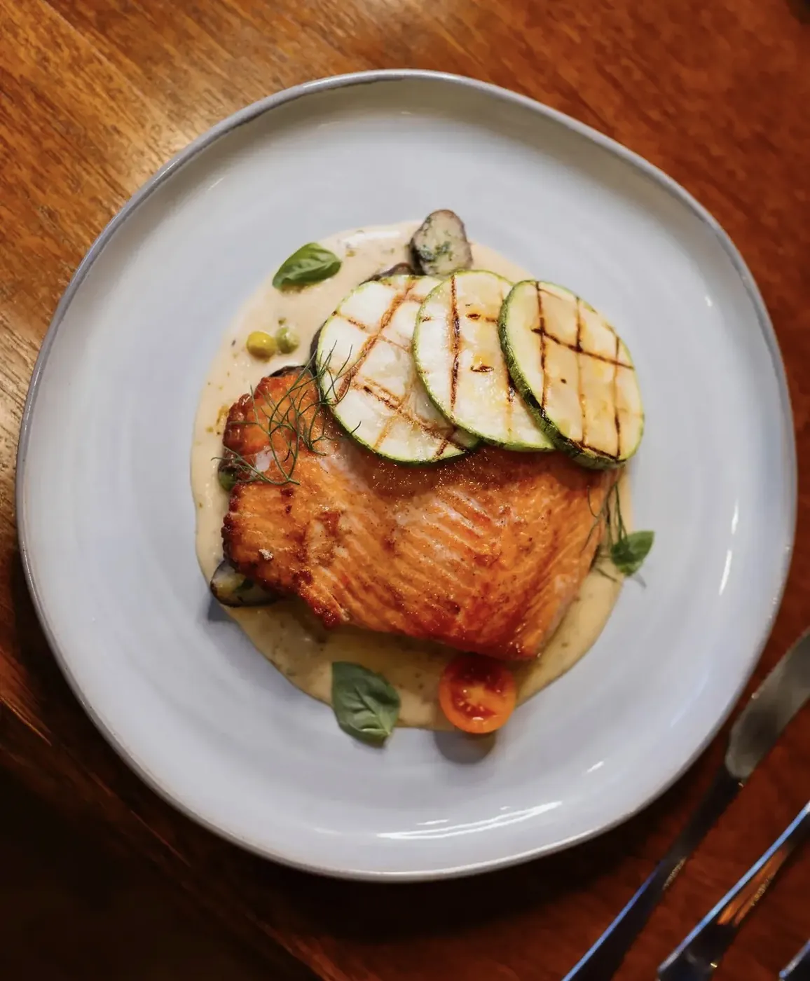 Salmón sellado con láminas de zucchini a la parrilla sobre crema de hierbas