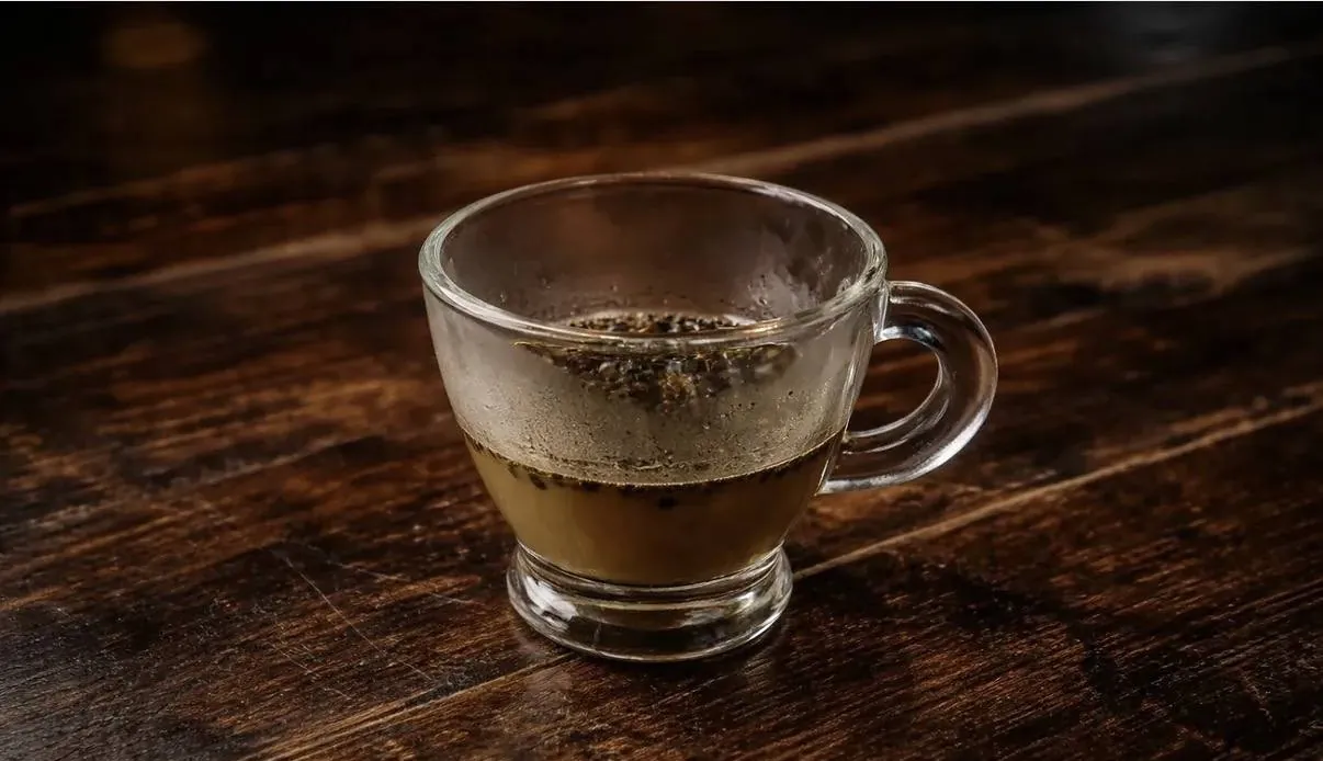 Caldo concentrado en taza de vidrio sobre mesa de madera