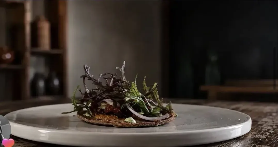 Tortilla de cañahua con hojas frescas sobre plato claro